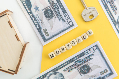 mortgage, loan and home purchase. Model of house, dollar bills, key on white and yellow isolated...