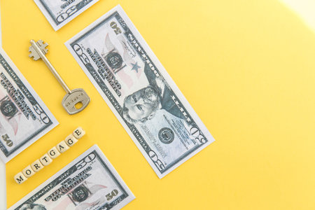 mortgage, loan and home purchase. Model of house, dollar bills, key on white and yellow isolated...