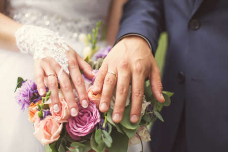 newlyweds bride and groom at a wedding hold hand, engagement and and wedding ringsの写真素材