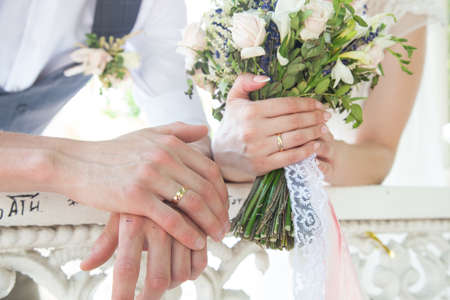 newlyweds bride and groom at a wedding hold hand, engagement and and wedding ringsの写真素材