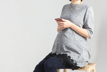 Beautiful young pregnant business woman using smart phone