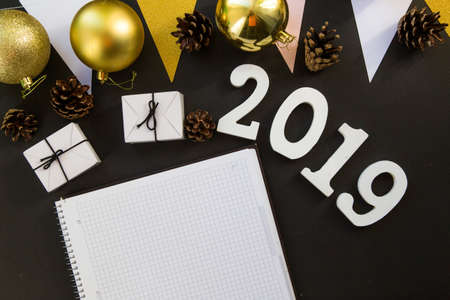 Happy New Year's layout. numbers 2019 notepad and free space for text. Christmas decorations, Christmas toys, gold stars. Goals for the new year. mock up mobile phone on black backgroundの写真素材