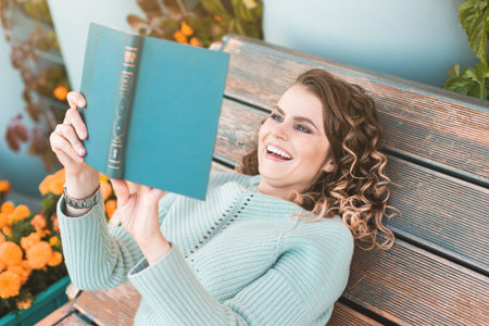beautiful, fashionable, beautiful girl reading a book. curly girl in headphones walks through the...