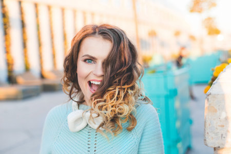 fashion portrait of young beautiful, fashionable, curly girl in headphones walks through the city....