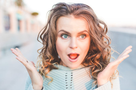 beautiful, fashionable, curly girl walks through the city. Joyful emotions on the face, smile, surprise, happiness. Beautiful smile with perfect white teeth.の写真素材