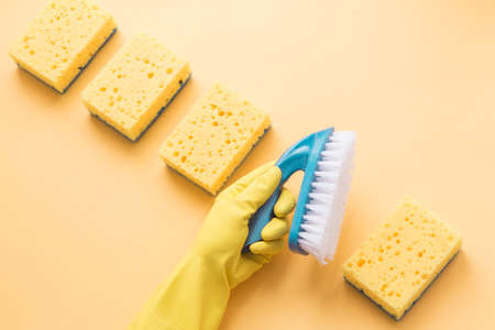 Flat lay Detergents and cleaning accessories and womens hands in rubber gloves in yellow color. Cleaning service concept. Flatlay, Top view.の写真素材