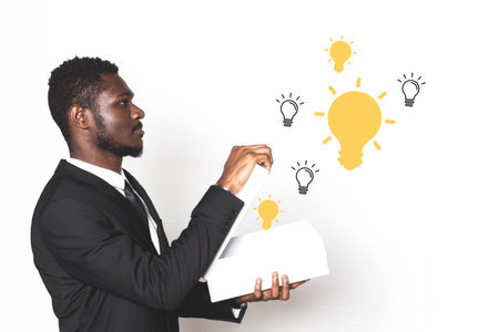 businessman afroamerican in a suit holds a box from which ideas come in the form of light bulbs....
