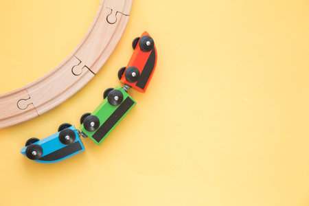 Kids toys frame on yellow backround, toy wooden railway and train. Top view. Flatlay. Copy space for...