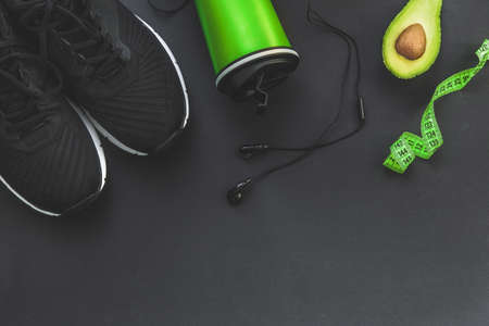 healthy lifestyle and fitness in sports, morning jogging. Sneakers, avocados, headphones and a water bottle on a black background. Top view and flatlayの写真素材