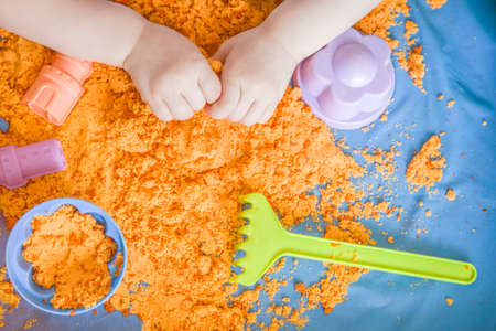 The hands of a child girl playing with kinetic sand. development of fine motor skillsの写真素材