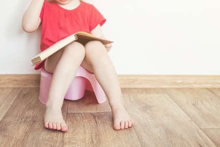 funny child girl sitting on chamberpot, Children's legs hanging down from a pot.の写真素材