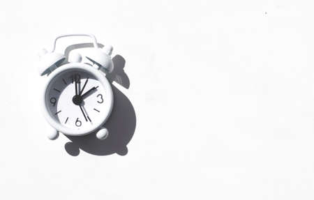 Desktop flatlay: alarm clock on a white background with sun shadowsの写真素材