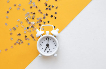 White table clock, alarm on yellow background, top view. Good morning. Minimalism, flatlay