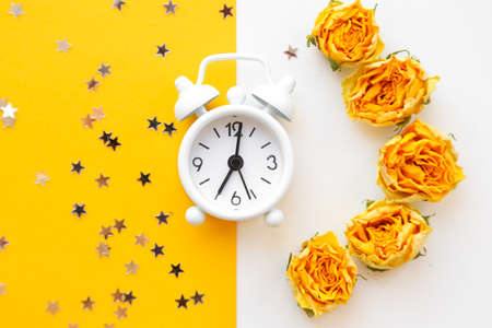 White table clock, alarm on yellow background, top view. Good morning. Minimalism, flatlayの写真素材