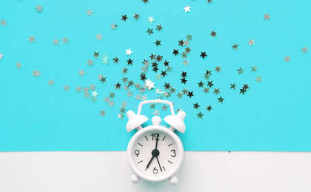 White table clock, alarm on blue background, top view. Good morning. Minimalismの写真素材
