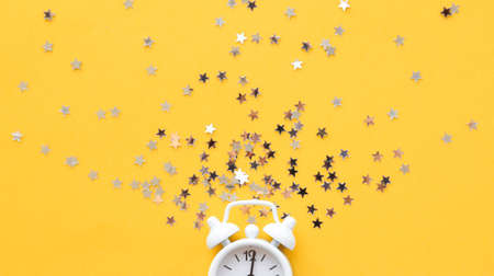 White table clock, alarm on yellow background, top view. Good morning. Minimalism, flatlayの写真素材