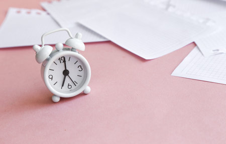 White table clock, alarm clock on a bright background, top view. Break at work in the office. Paper, flatlayの写真素材