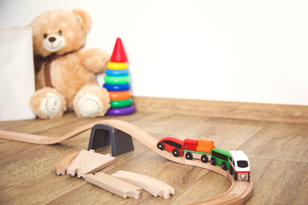 Little girl plays with toys, wooden railway and train