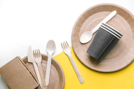 eco friendly disposable dishes made paper on white marble background. Draped spoons, fork, knives, plate with paper cups. recycling conceptの写真素材