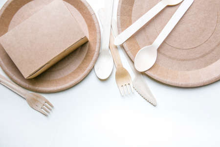eco friendly disposable dishes made paper on white marble background. Draped spoons, fork, knives, plate with paper cups. recycling conceptの写真素材