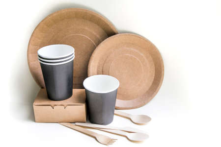eco friendly disposable dishes made paper on white marble background. Draped spoons, fork, knives, plate with paper cups. recycling conceptの写真素材