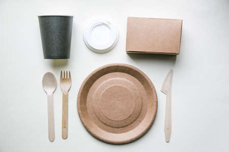 eco friendly disposable dishes made paper on white marble background. Draped spoons, fork, knives, plate with paper cups. recycling conceptの写真素材