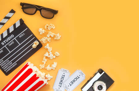 Cinema party concept. movie tickets, clapperboard, pop corn and 3d glasses in a yellowの写真素材