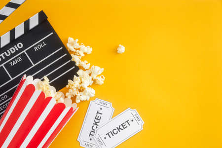Cinema party concept. movie tickets, clapperboard, pop corn and 3d glasses in a yellowの写真素材