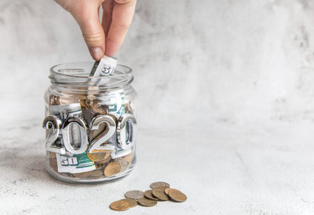 Budget 2020. Glass jar with money, coins and notes, savings, loans and mortgages.