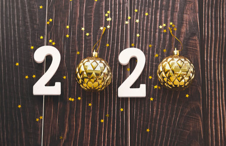 Happy New Year 2020 flatlay composition. Christmas toys and white snowflakes on a black wooden...