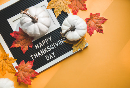 FLatlay composition happy thanksgiving day . pumpkins and autumn leaves on an orange background.