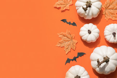 Happy Hallooween backgroung. Flat lay composition on orange paper. White pumpkins and bats.