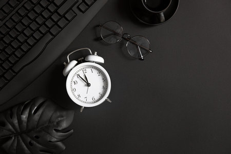 Desk with laptop, eye glasses, pen and a cup of coffee. Top view with copy space. totally black.