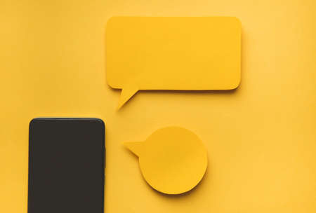 Smartphone and Message bubbles chat papper on yellow background.の写真素材
