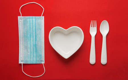 valentines day during the pandemic, 14 february 2021. dishes and a medical mask on the tableの写真素材