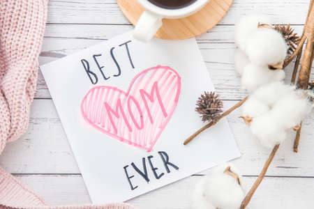 Beautiful flat lay composition, cup cotton branch and card on white wooden background. Happy Mother Dayの写真素材