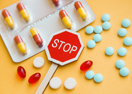 Sign Stop drugs. Colorful pile of medicines and painkillers on yellow backgroundの写真素材