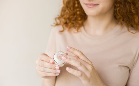 young skin care concept. Hands of a woman about to apply face cream.