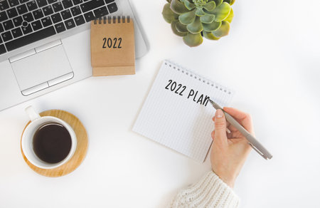 female hand writing down to-do list and plans for 2022 to notebook. Goals for next yearの写真素材