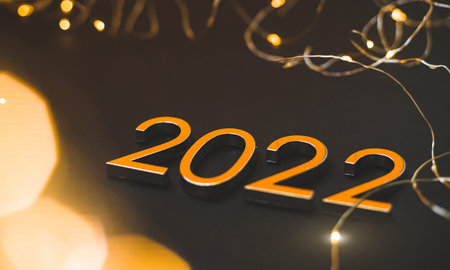 Gold numbers 2022 on black background with golden bokeh
