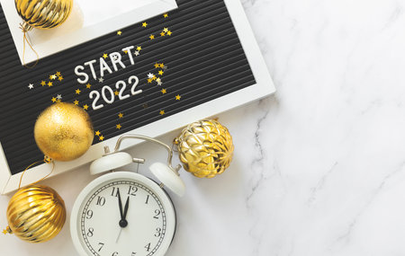 start new 2022 year. christmas composition on table, alarm clock with golden balls