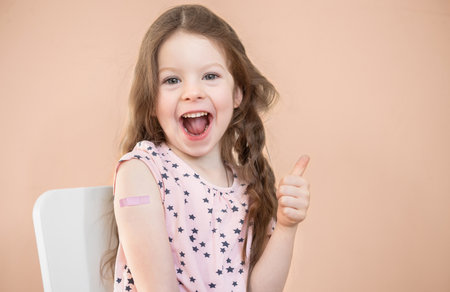 Photo portrait baby girl got vaccine, smiling pointing finger recommending isolatedの写真素材