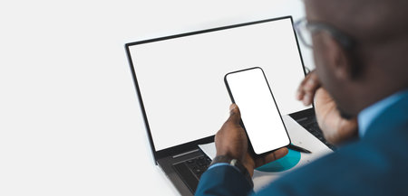 Close up businessman using modern laptop and smartphone gadget, business man consult client work on computer and cellphone device at workplace, white mockup screenの写真素材