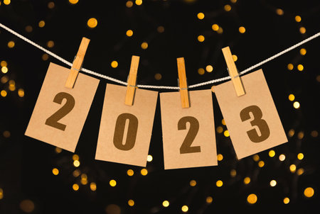 The year 2023 on pinned cards hanging from a string. Bookeh background