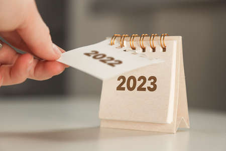 a womans hand turns over a calendar sheet. year change from 2022 to 2023の写真素材