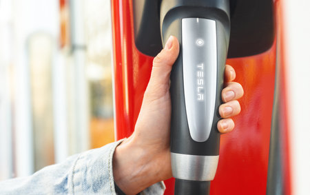 Astana, Kazahstan - October 15, 2022: electric car Tesla charging on supercharging station. Hand close upのeditorial素材
