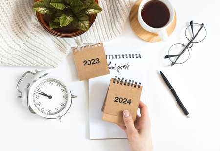 Womans hand holds calendar, year change from 2023 to 2024.の写真素材