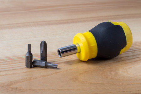 Small screwdriver with three bits on wooden table