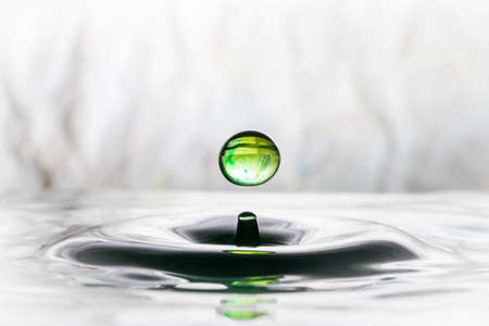Green water drop bouncing on water surfaceの写真素材