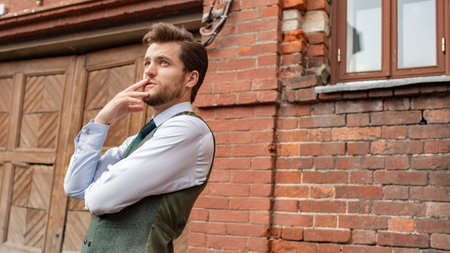 a man standing near a brick wall